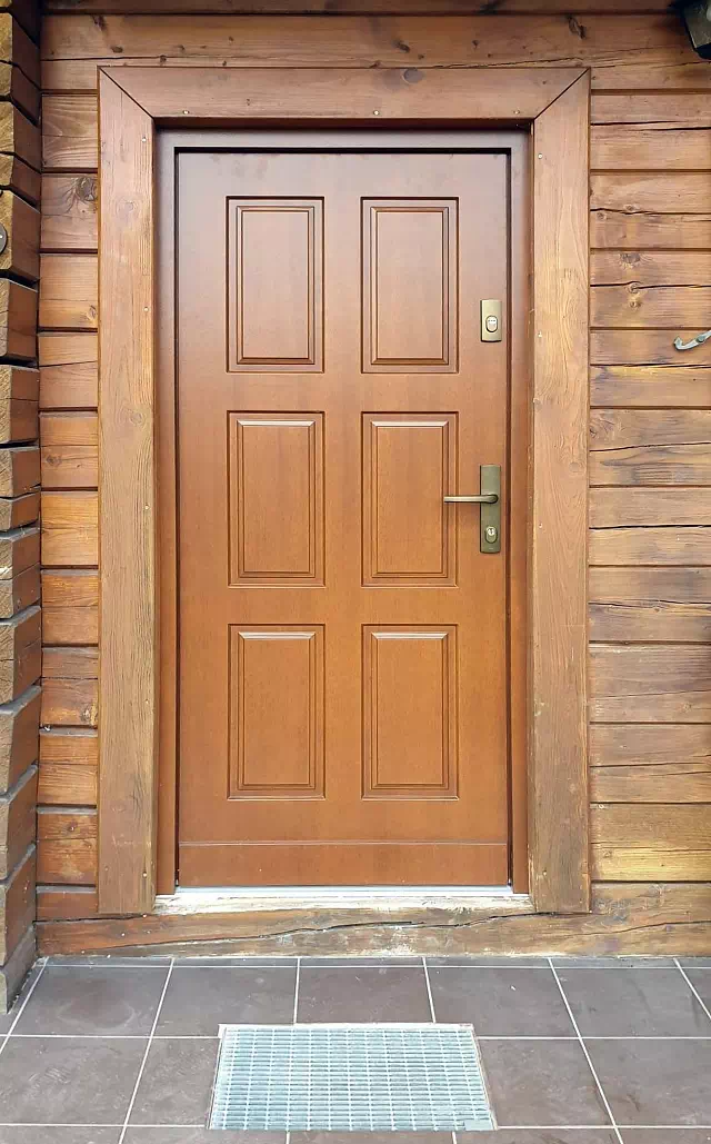 Widok elewacji domu z zamontowanymi drzwiami wzór 534,4 wymalowanymi w kolorze złoty dąb.