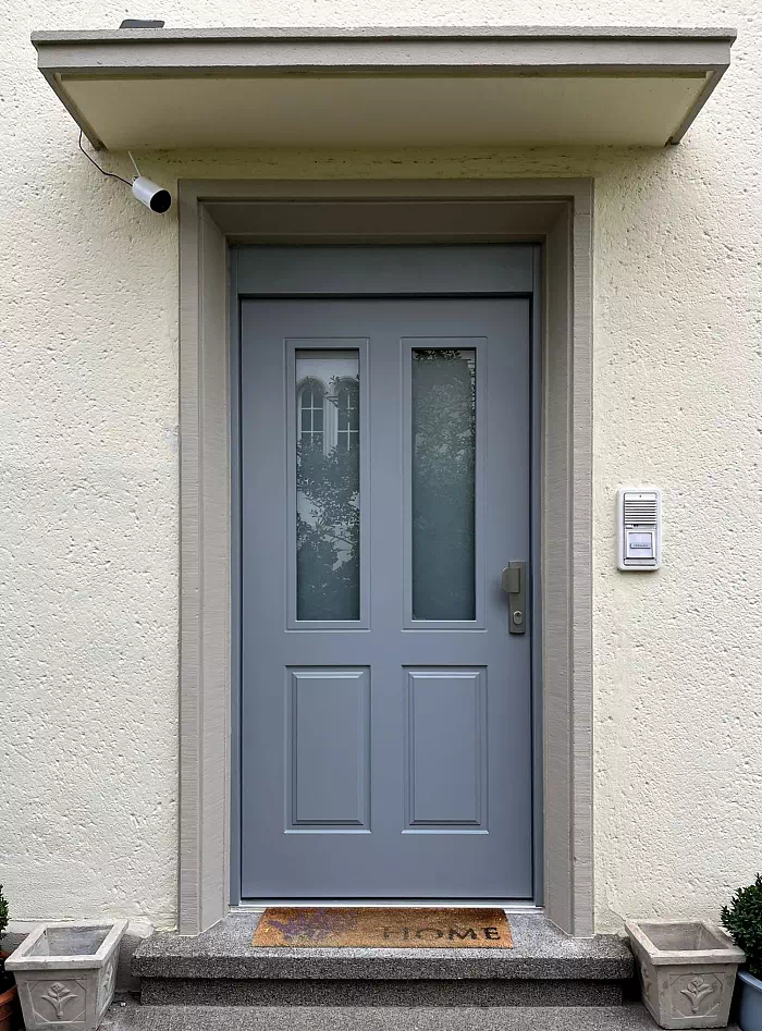 Widok elewacji domu z zamontowanymi drzwiami wzór 534,9b wymalowanymi w kolorze błękitne.