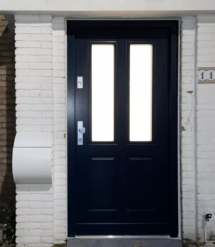 Widok elewacji domu z zamontowanymi drzwiami wzór 534,9b wymalowanymi w kolorze czarne.