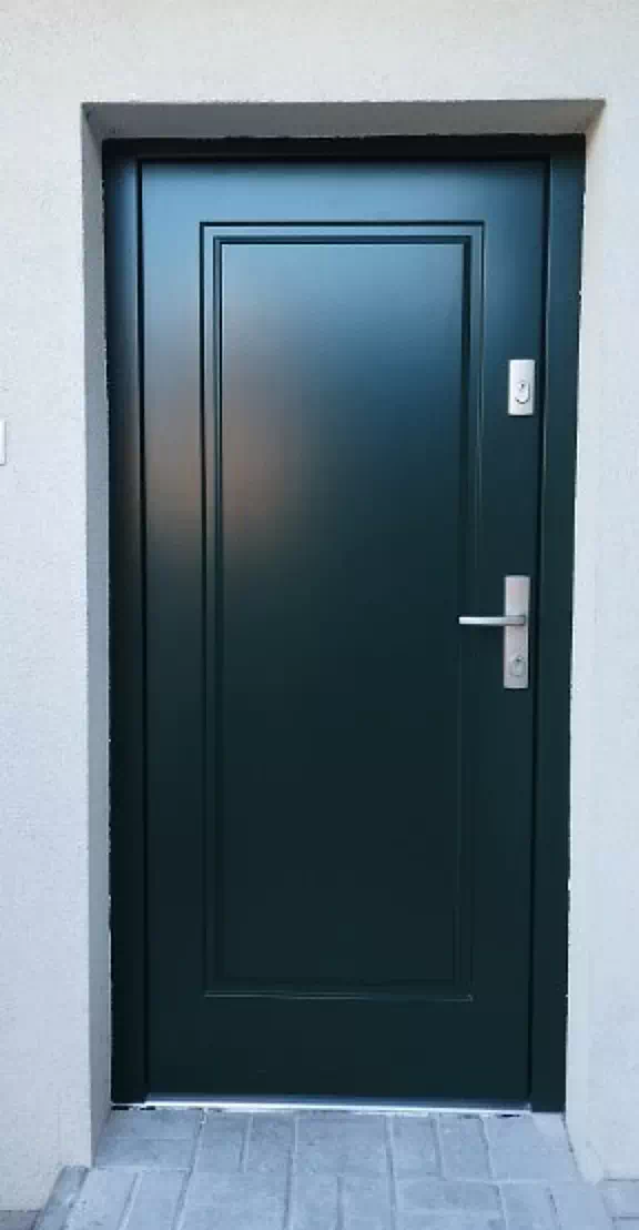 Widok elewacji domu z zamontowanymi drzwiami wzór 535,5 wymalowanymi w kolorze zielone.