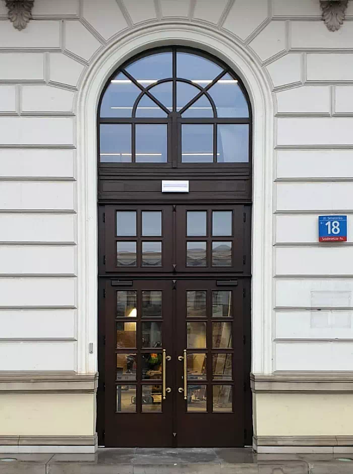 Widok elewacji domu z zamontowanymi drzwiami wzór 897,1 wymalowanymi w kolorze orzech ciemny.